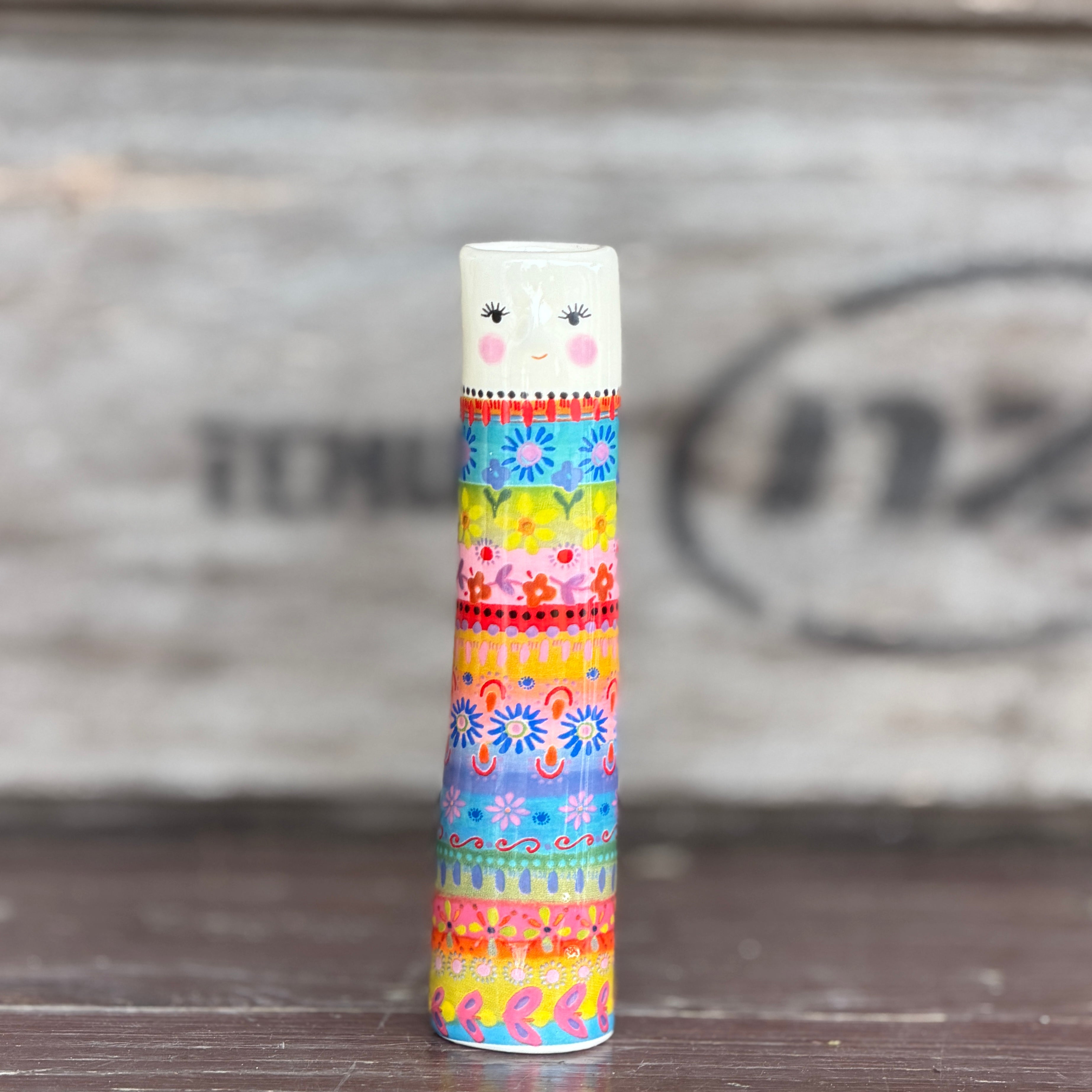 A tall cylindrical mini bud vase with floral design and text ' Life is better with you in it'.