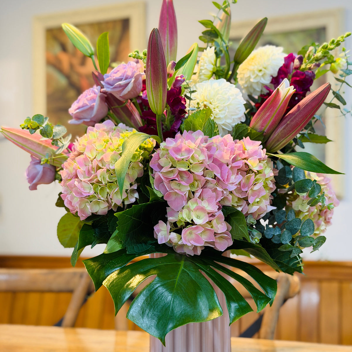 Floral arrangement of pink hydrangeas, lilies and roses and white dahlias in a pink vase