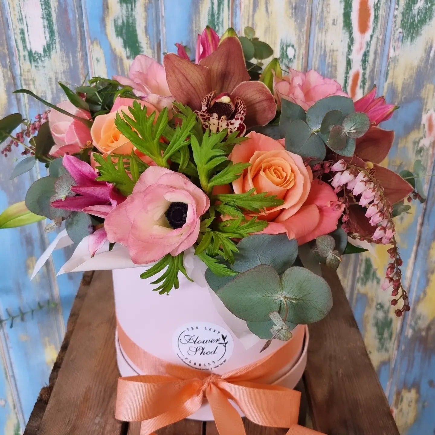 Bouquet of flowers in a white box with an orange ribbon against a colorful background