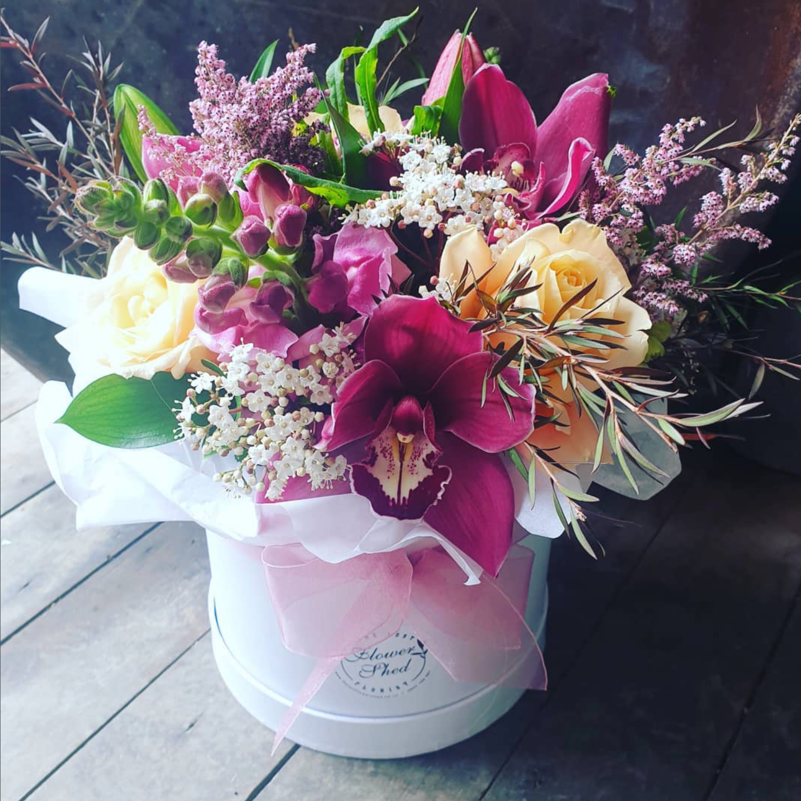 Bouquet of flowers in a white box on a wooden floor