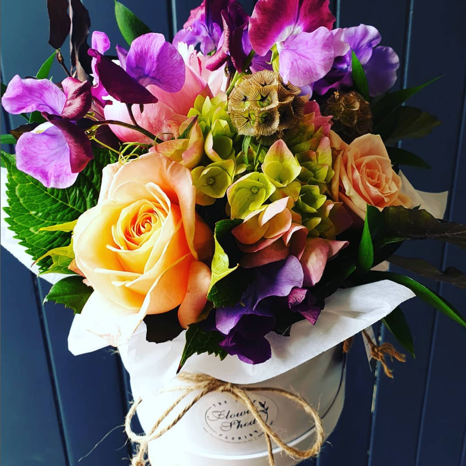 Bouquet of colorful flowers in a white vase against a blue background