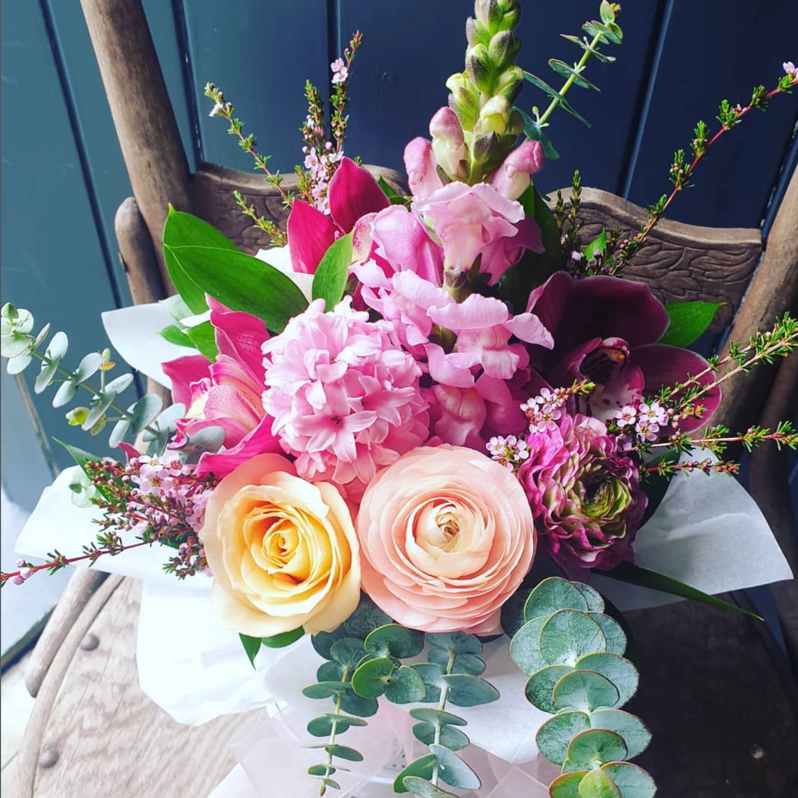 Bouquet of pink, yellow, and purple flowers with green leaves on a wooden surface.