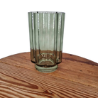Green glass vase on a wooden surface with a white background