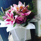 Bouquet of pink and purple flowers in a white box against a blue wooden background