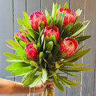 Bouquet of pink protea flower stems held in a bunch
