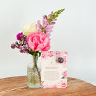 A bud vase with a card with a blooming tea ball with affirmation message