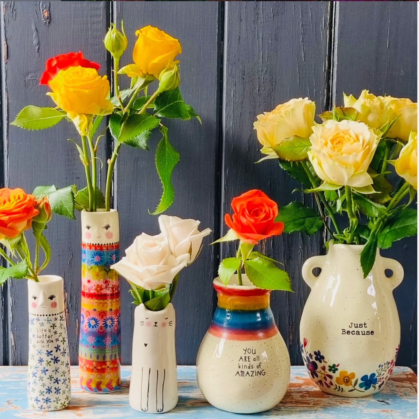 A tall cylindrical mini bud vase with floral design and text ' Life is better with you in it'.